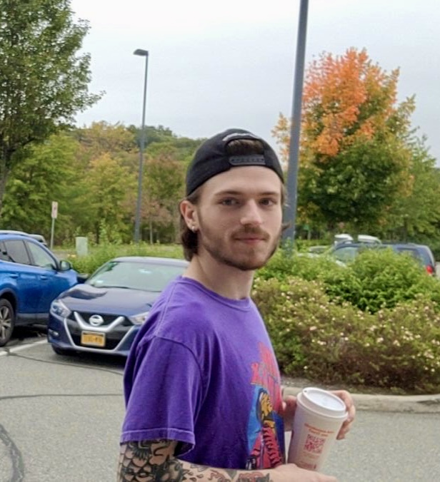 Me standing with a coffee cup in my hand, turning my head right to look at the camera.